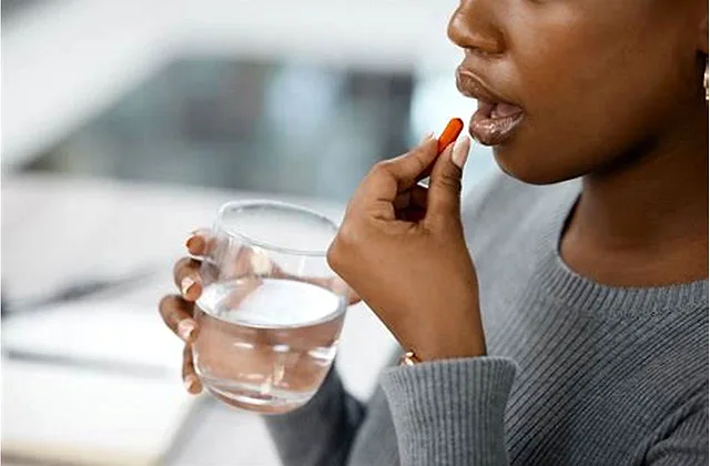 Tylenol acetaminophen tablet next to a glass of water, illustrating practical everyday usage